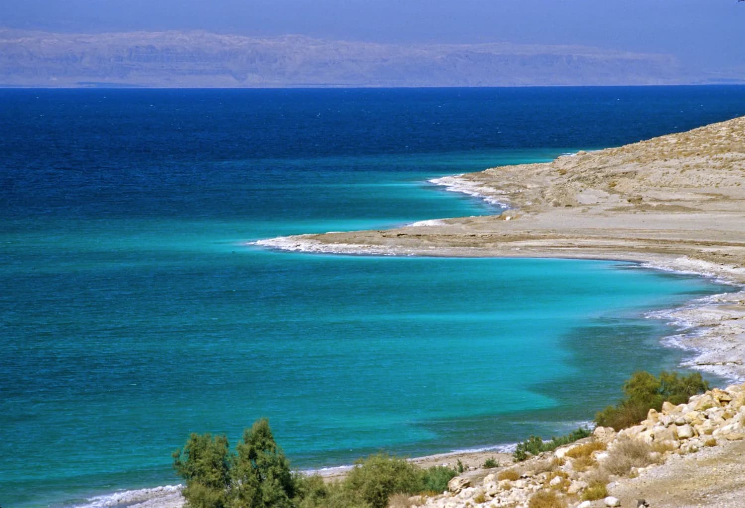 The mineral shoreline and blue water of the Dead Sea in Jordan