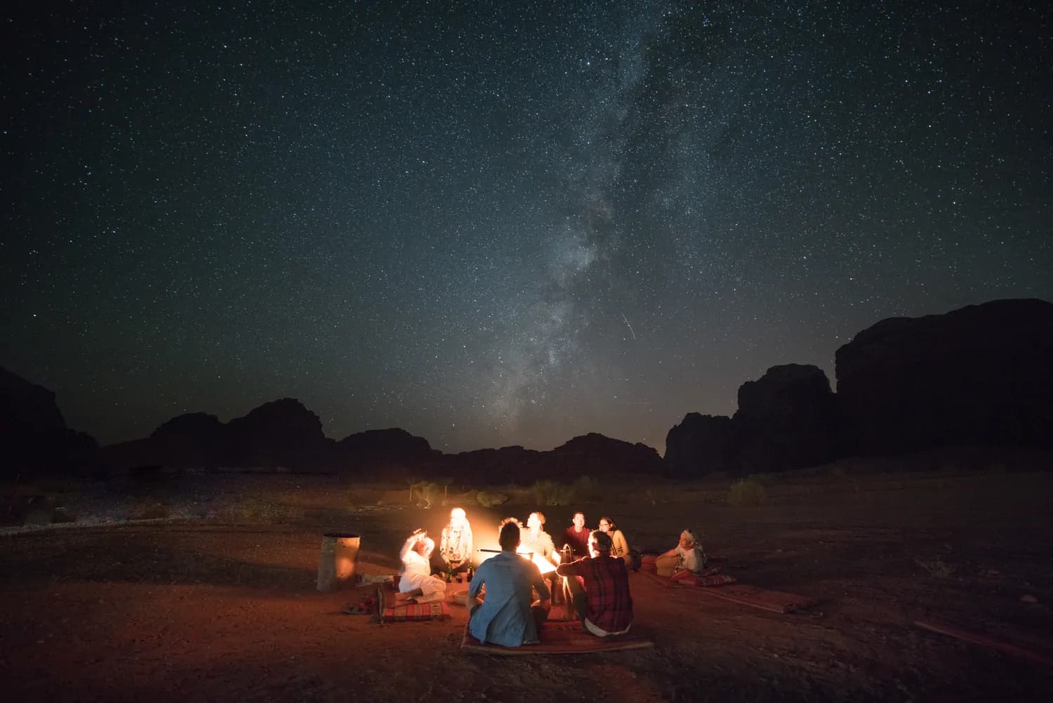 Travelers around a fire beneath the stars in Wadi Rum, Jordan